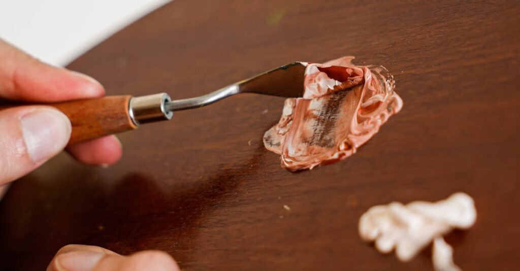 Detailed view of an artist mixing paint on a wooden palette using a spatula. Perfect for creative projects.