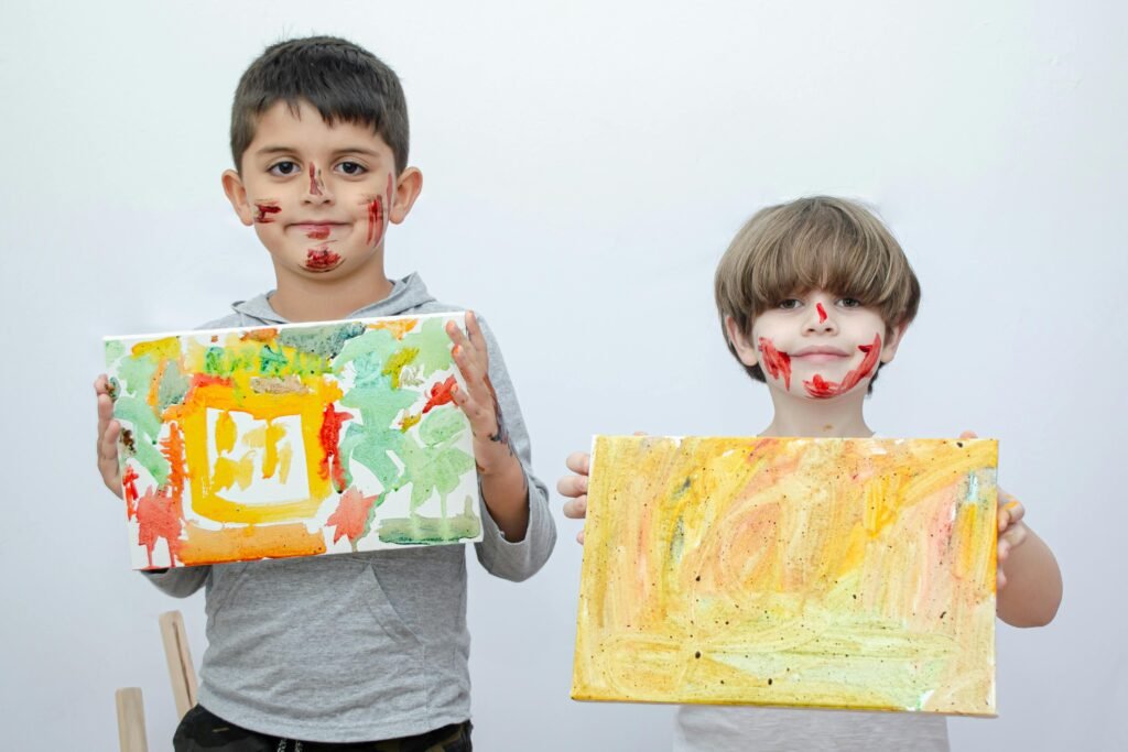 Two children proudly display their colorful paintings, with playful face paint adding to the fun.