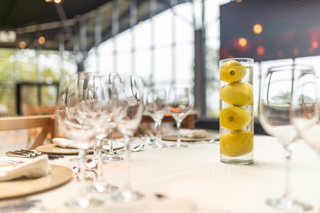 A sophisticated table setting with glassware and a lemon-filled vase in a modern restaurant.