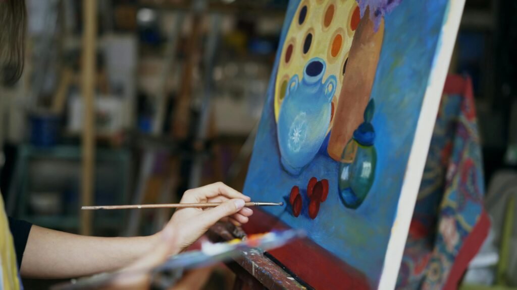 Close up of artist's hand painting a still life on canvas in a studio environment.