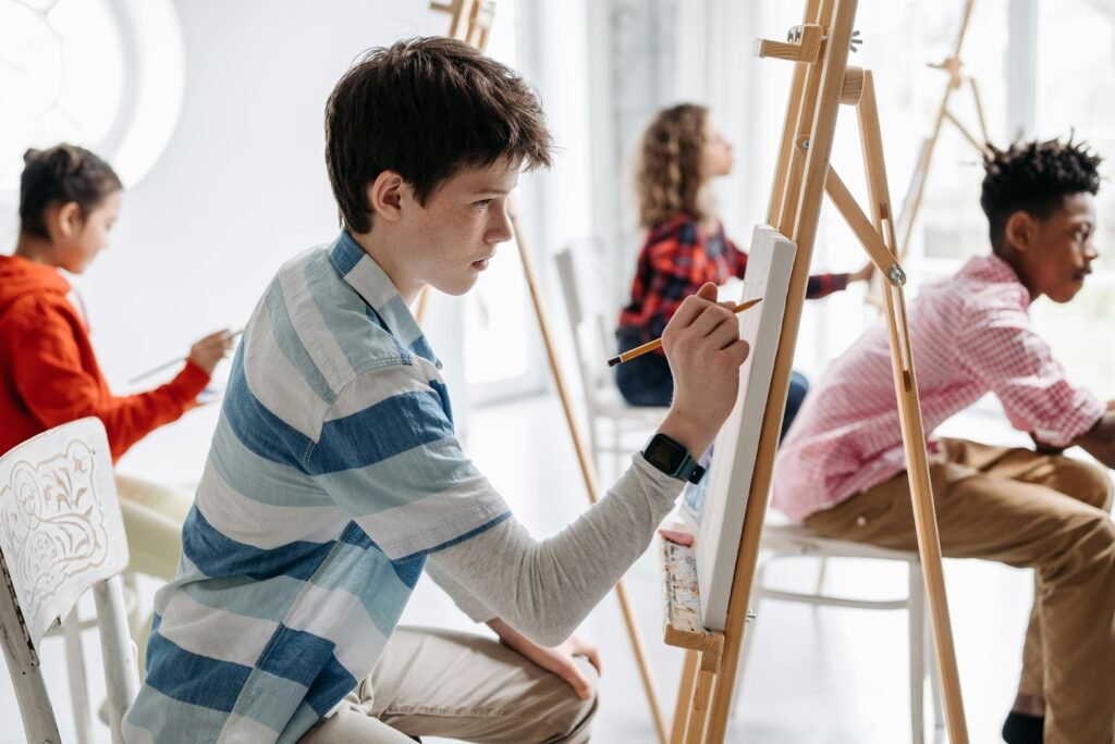 Teens actively participating in an art class indoors, focused on painting and creativity.