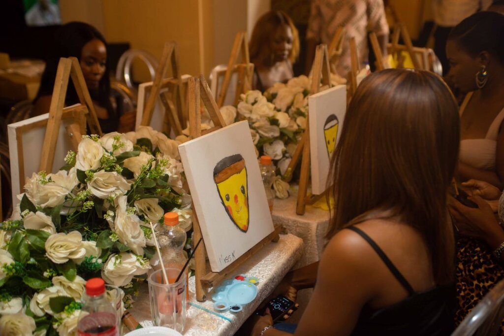 Group of women enjoying a paint and sip party, painting canvases indoors with vibrant decor.
